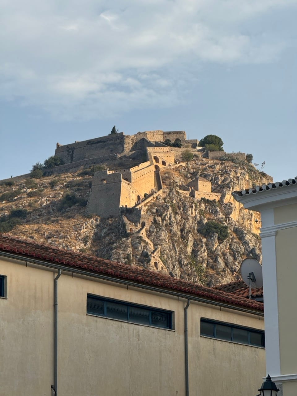 Blick aus einer Gasse auf die Burgteile am Berghang, inklusive Aufgang.