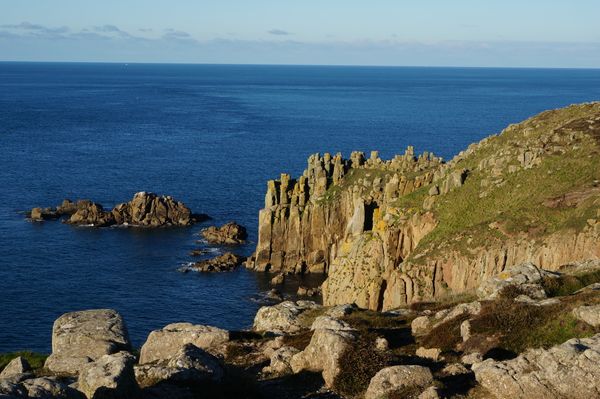 Spitzer säulige Klippenvorsprung, dazu ein Klippenverlauf. Aufgenommen bei Land's End in Cornwall.